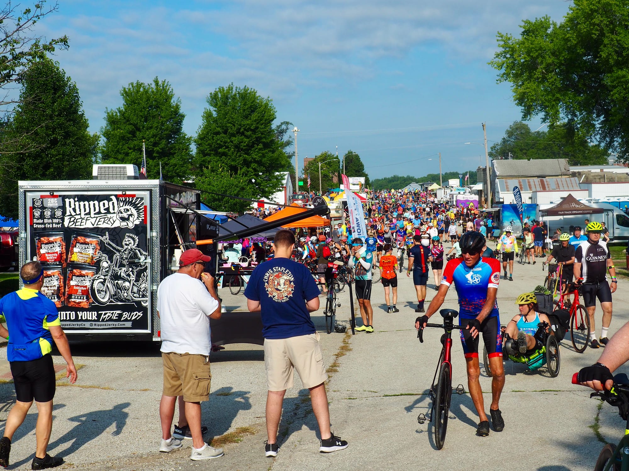 A town street filled with people, bikes, and vendor trucks.