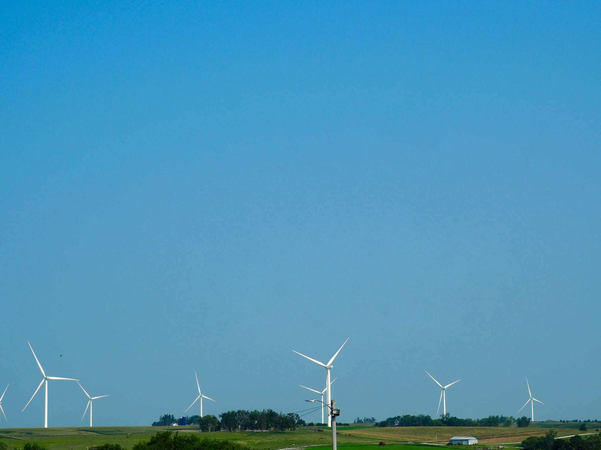 Giant wind turbines in the distance with clear skies overhead.